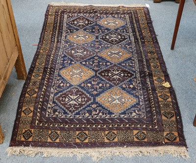 Lot 1219 - A Baluch rug, the indigo diamond lattice field...