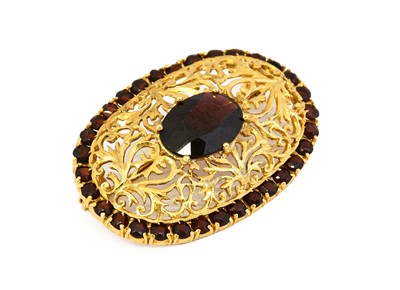 Lot 1063 - A garnet brooch, an oval cut garnet within a...