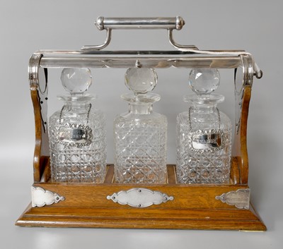 Lot 33 - An Oak and Silver Plated Three Bottle Tantalus,...