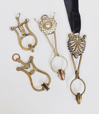 Lot 1038 - Two White Metal Ornamental Skirt Lifters, and...